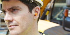 Photo of construction worker in hard hat wearing ear plugs
