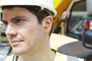 Photo of construction worker in hard hat wearing hearing protection (ear plugs)